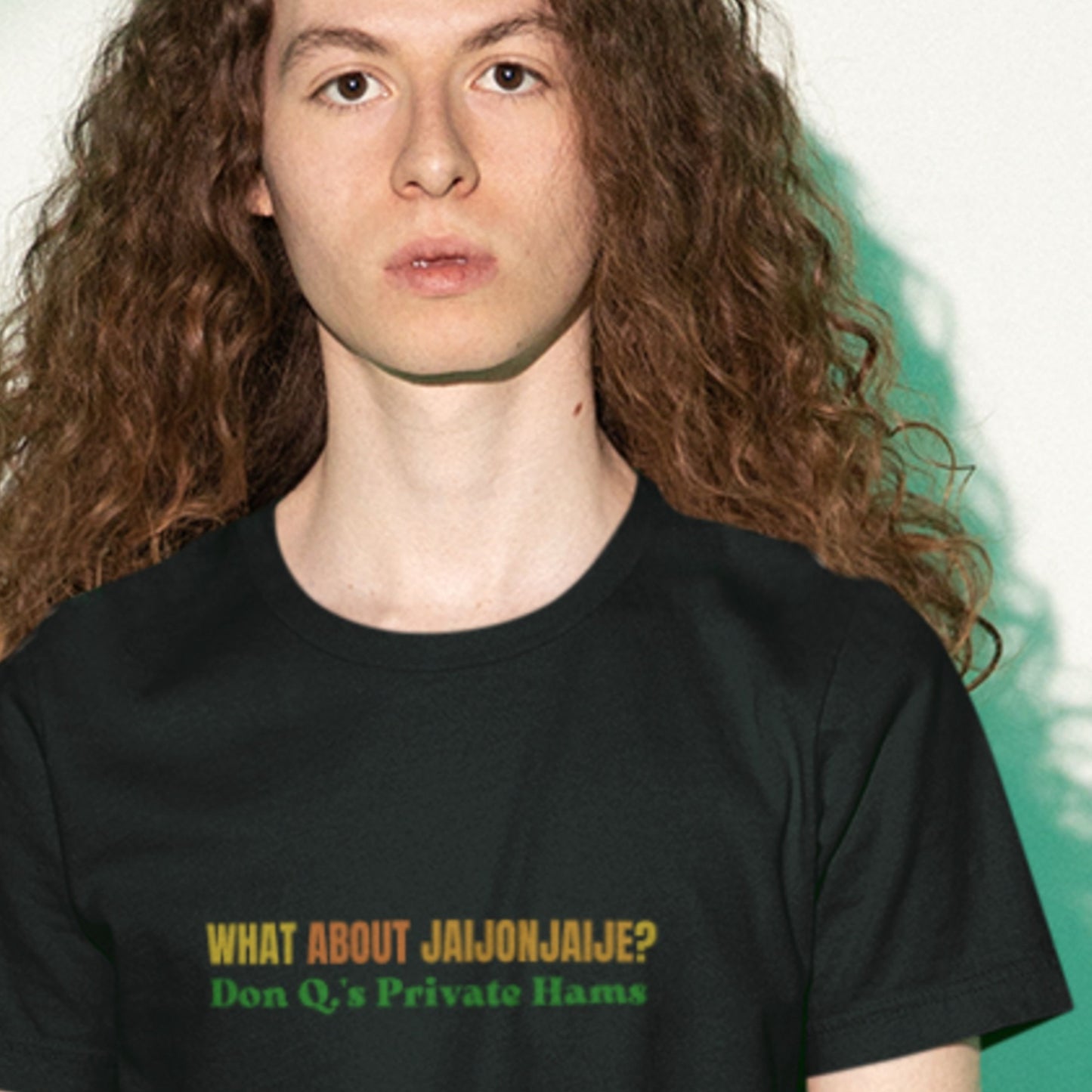 Person wearing a black t-shirt with humorous colorful text on a beige background.