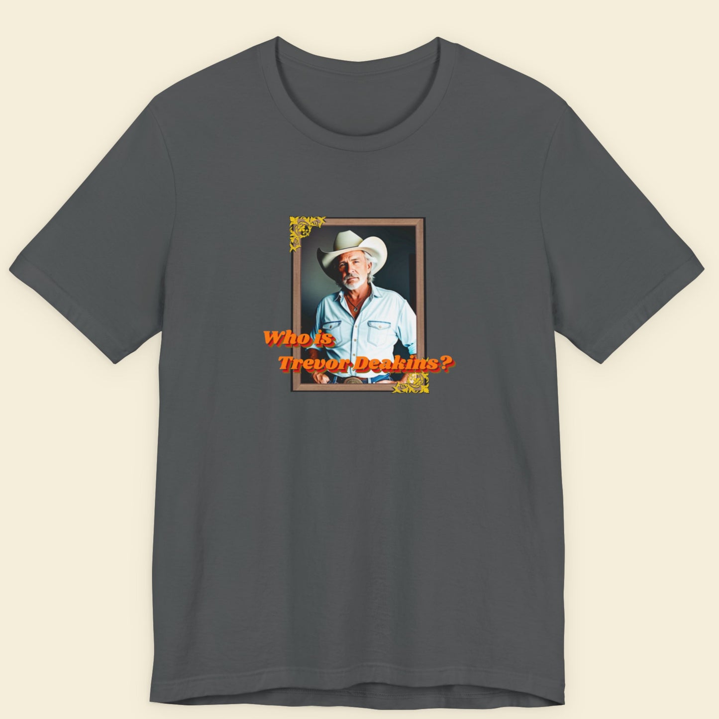Gray t-shirt with a graphic of a man in a cowboy hat and text 'Who is Trevor Deakins?' on a beige background