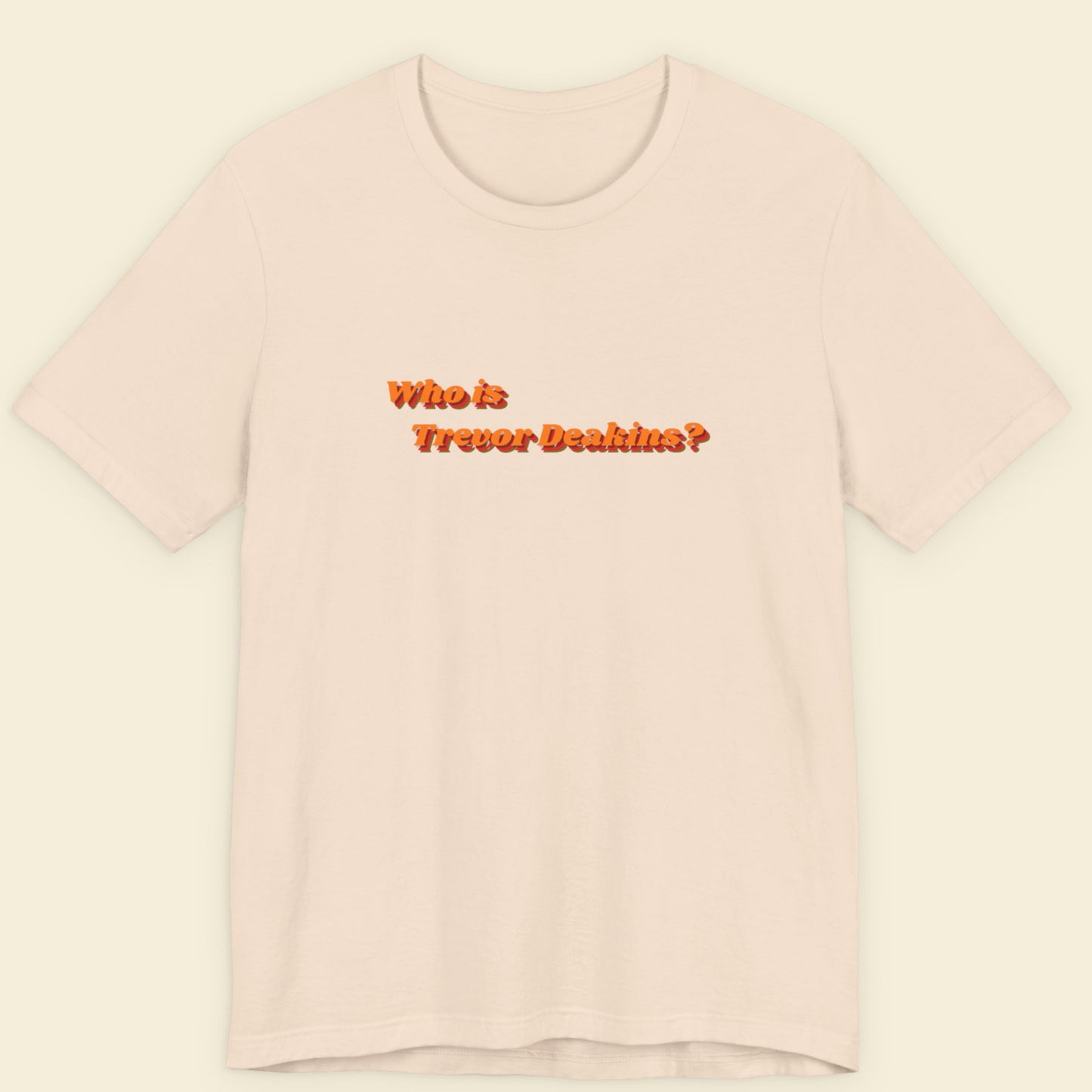 Pink t-shirt with text 'Who is Trevor Deakin?' on a beige background