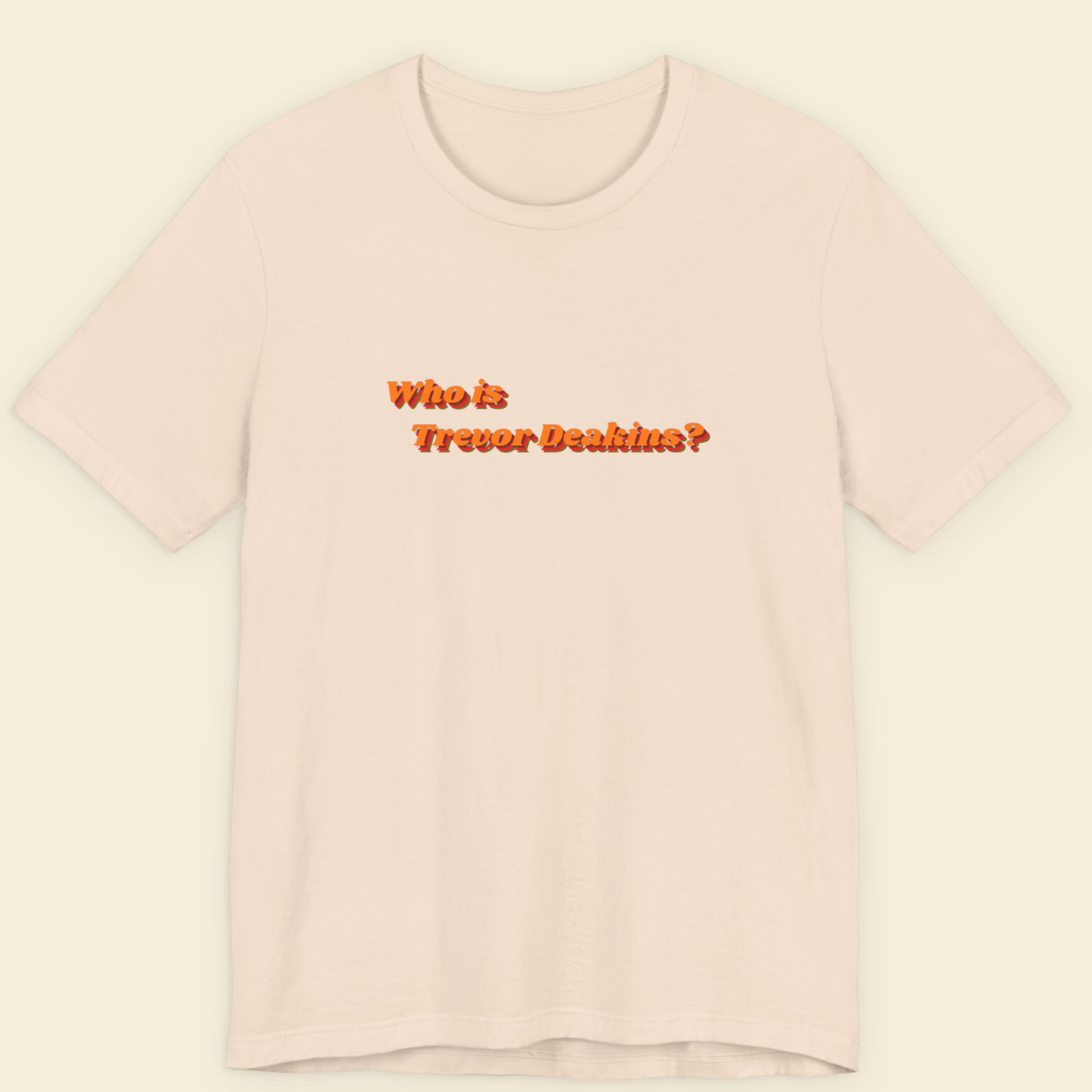 Pink t-shirt with text 'Who is Trevor Deakin?' on a beige background
