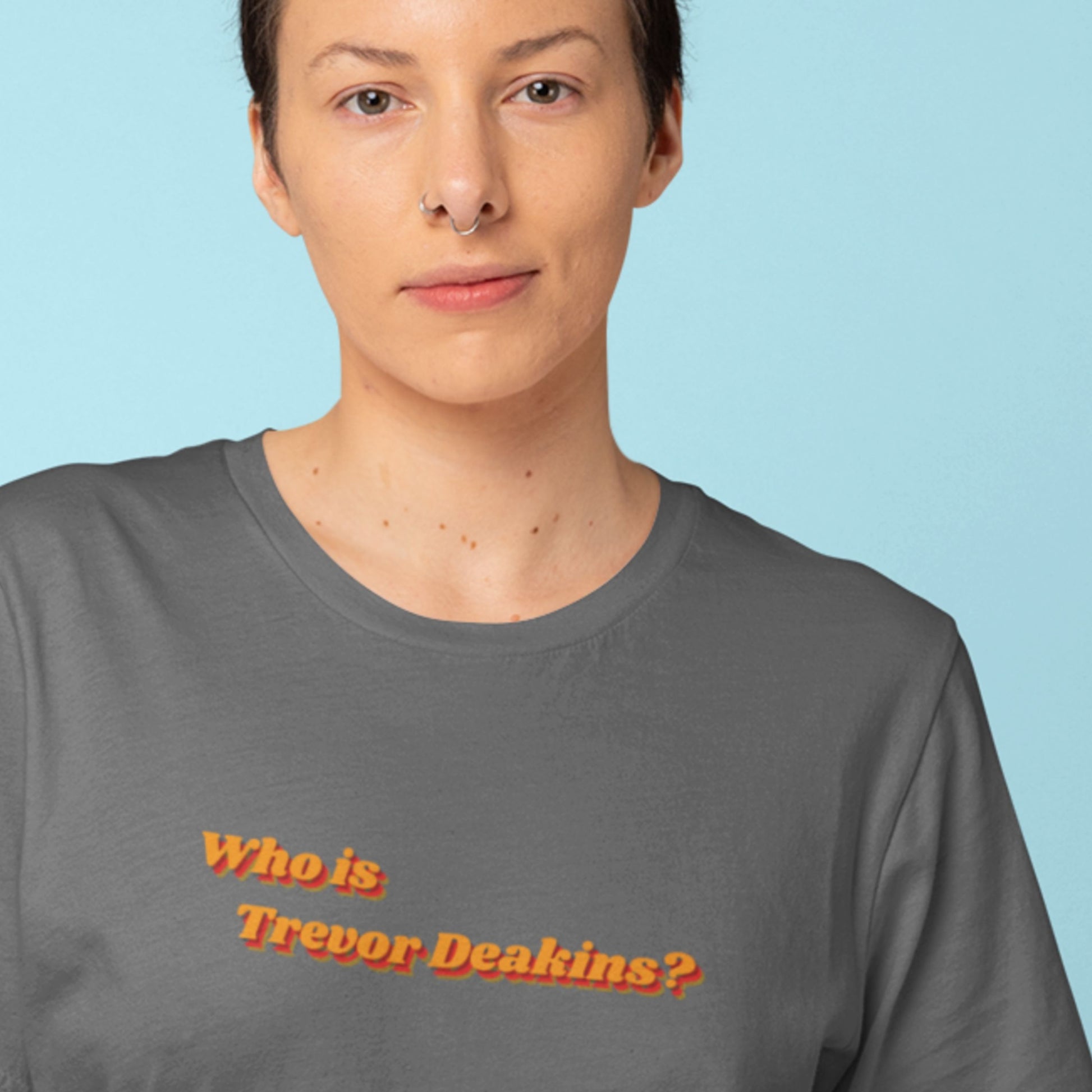 Person wearing a gray t-shirt with 'Who is Trevor Deakins?' text on a light blue background