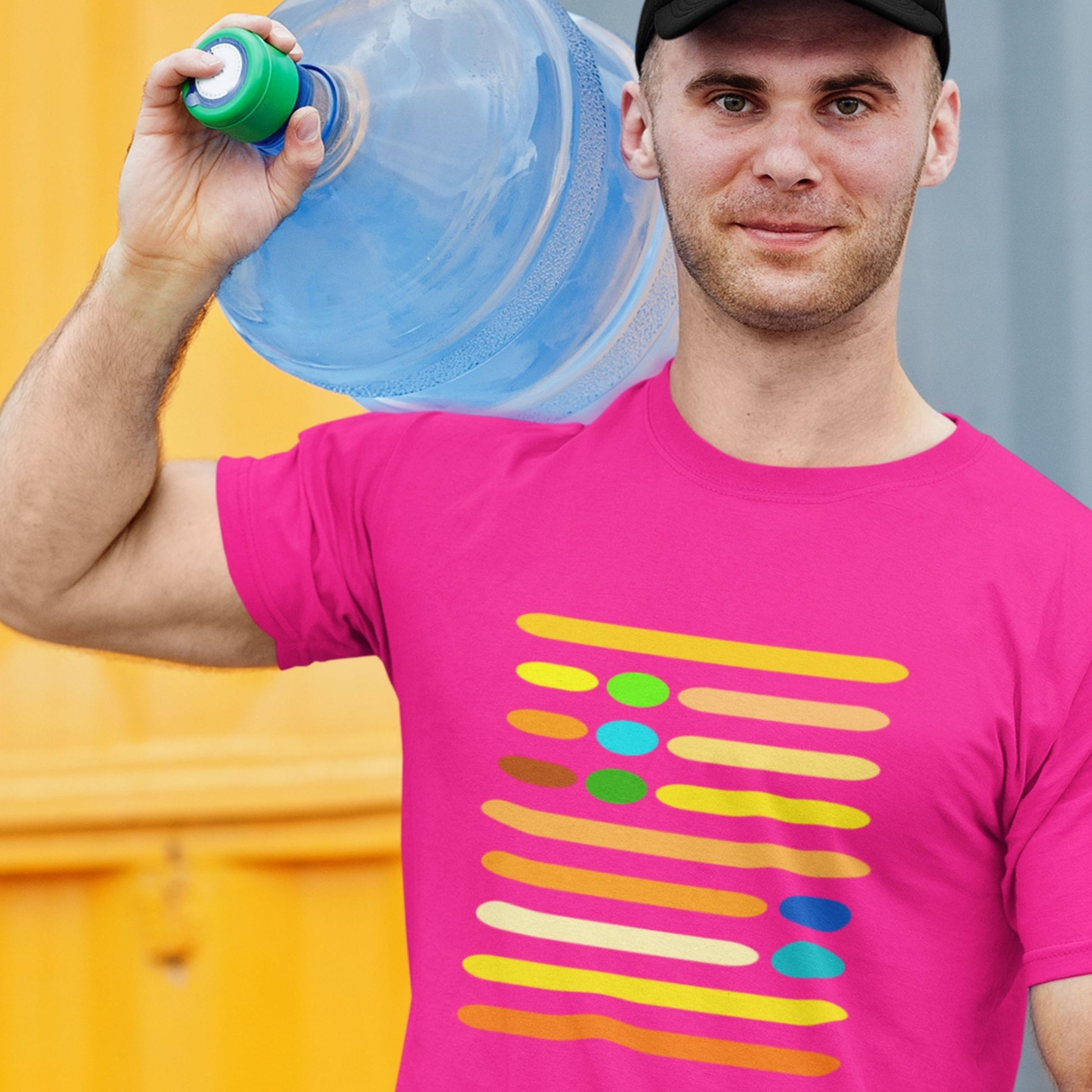 Man wearing a pink t-shirt with colorful design, holding a water bottle against a multicolored background.