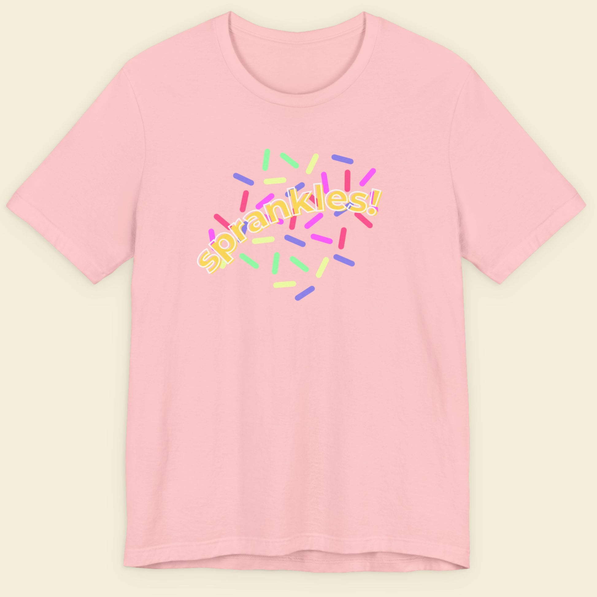 Pink t-shirt with colorful 'sprankles!' design on a beige background.
