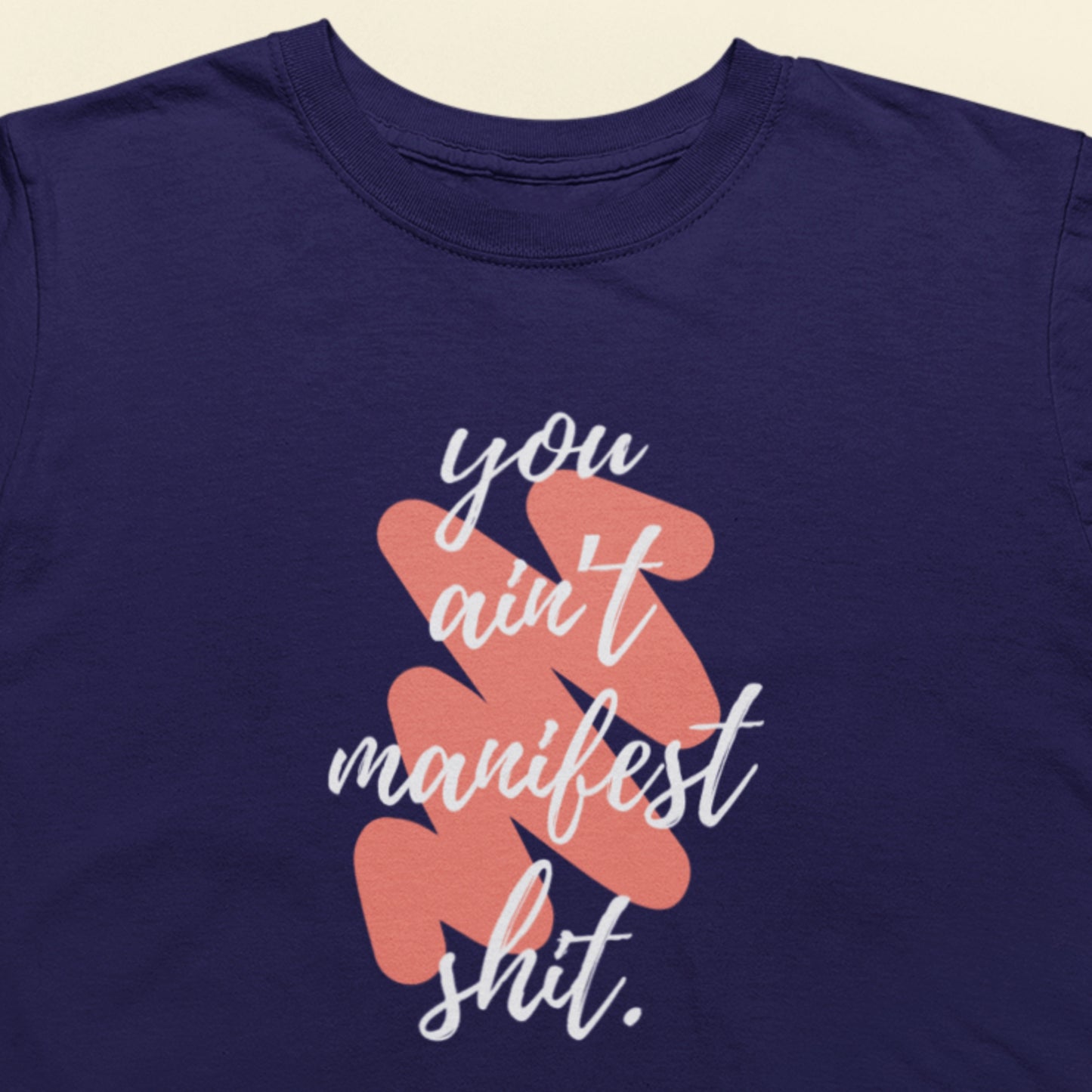 Navy blue t-shirt with white and coral text on a beige background
