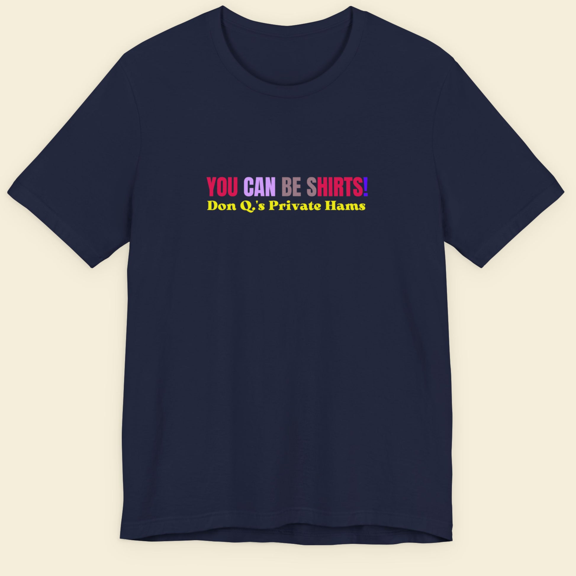 Navy blue t-shirt with multicolored 'you can be shirts!' text on a beige background.