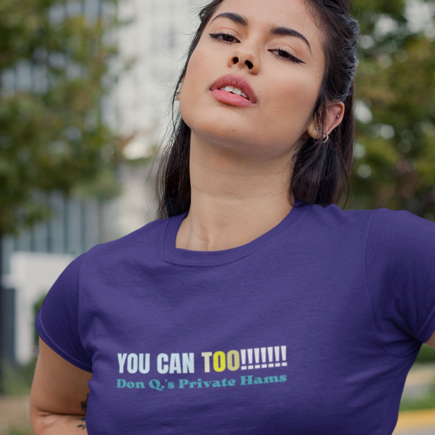 Woman wearing a blue t-shirt with humorous text outdoors.