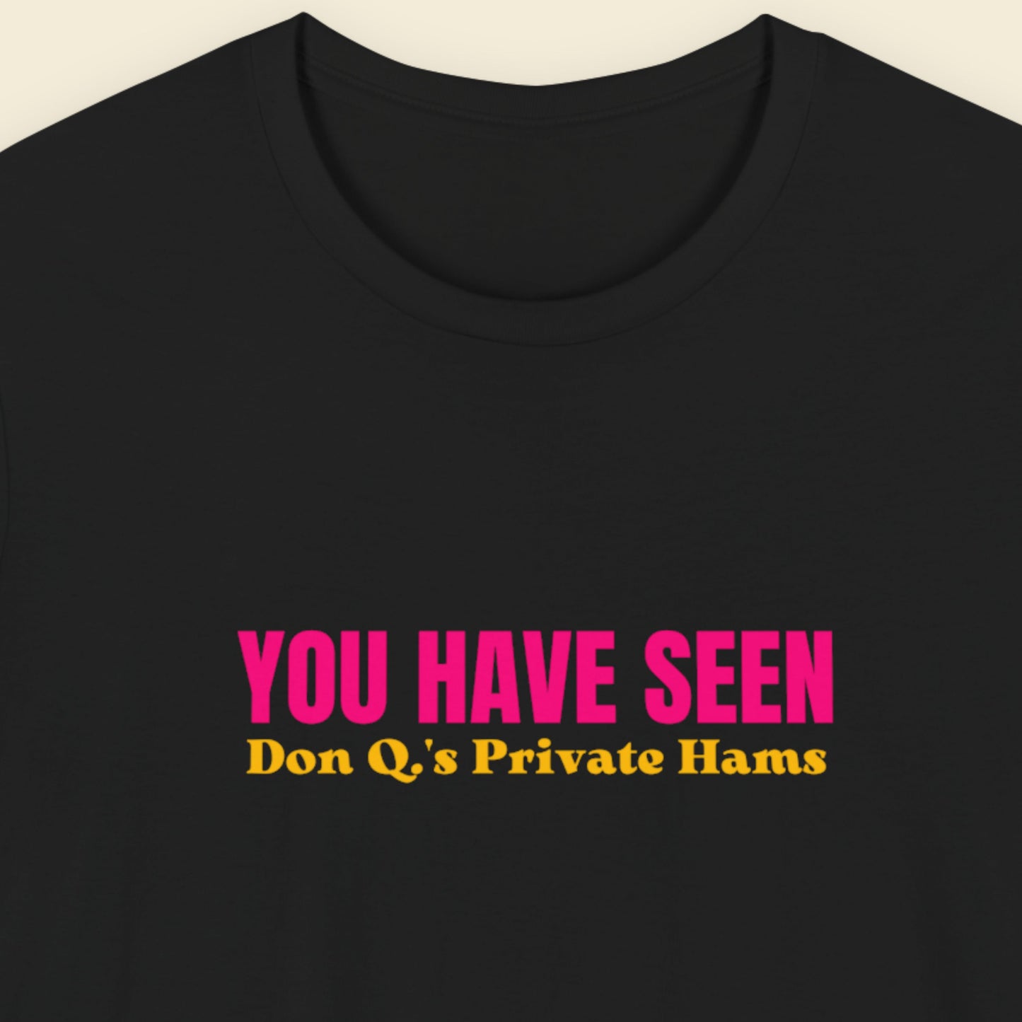 Black t-shirt with nonsensical multi-colored text on a beige background.