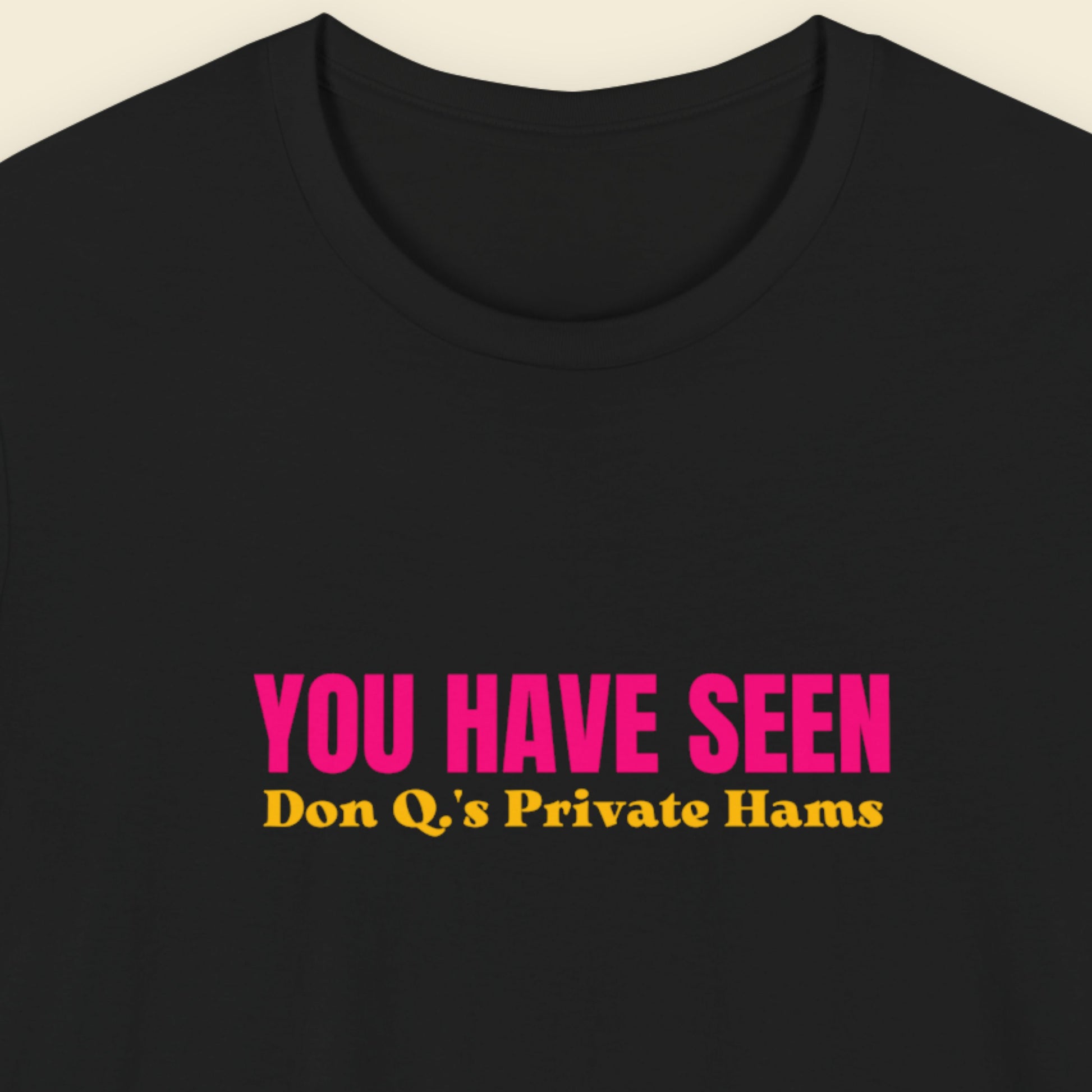 Black t-shirt with nonsensical multi-colored text on a beige background.