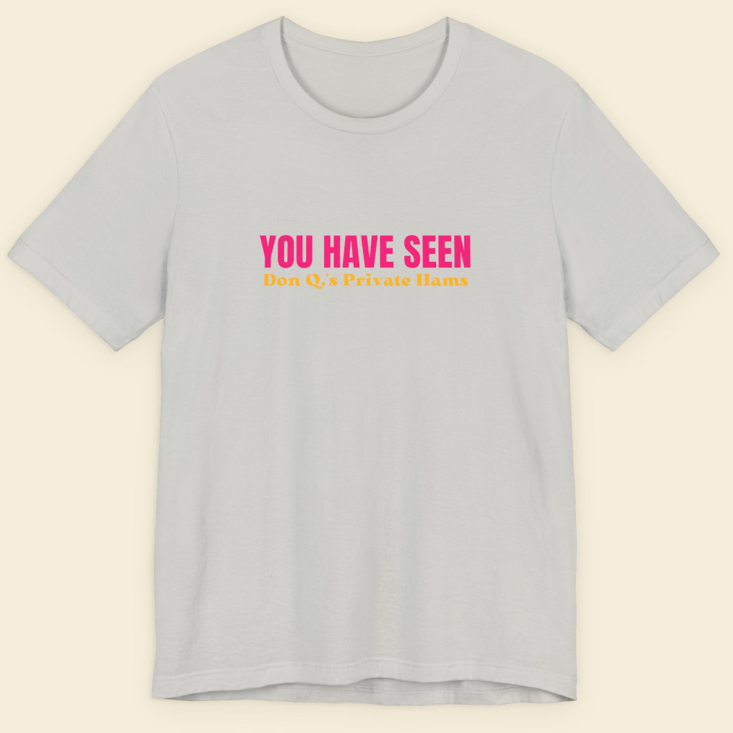 Light grey t-shirt with nonsensical multi-colored text on a beige background.