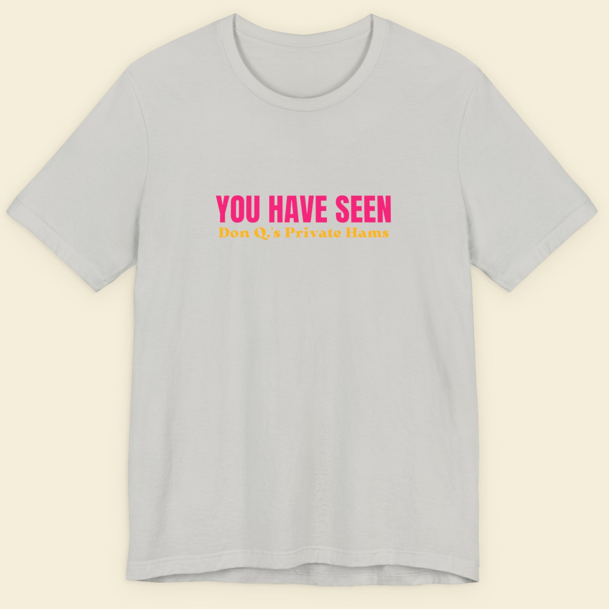 Light grey t-shirt with nonsensical multi-colored text on a beige background.