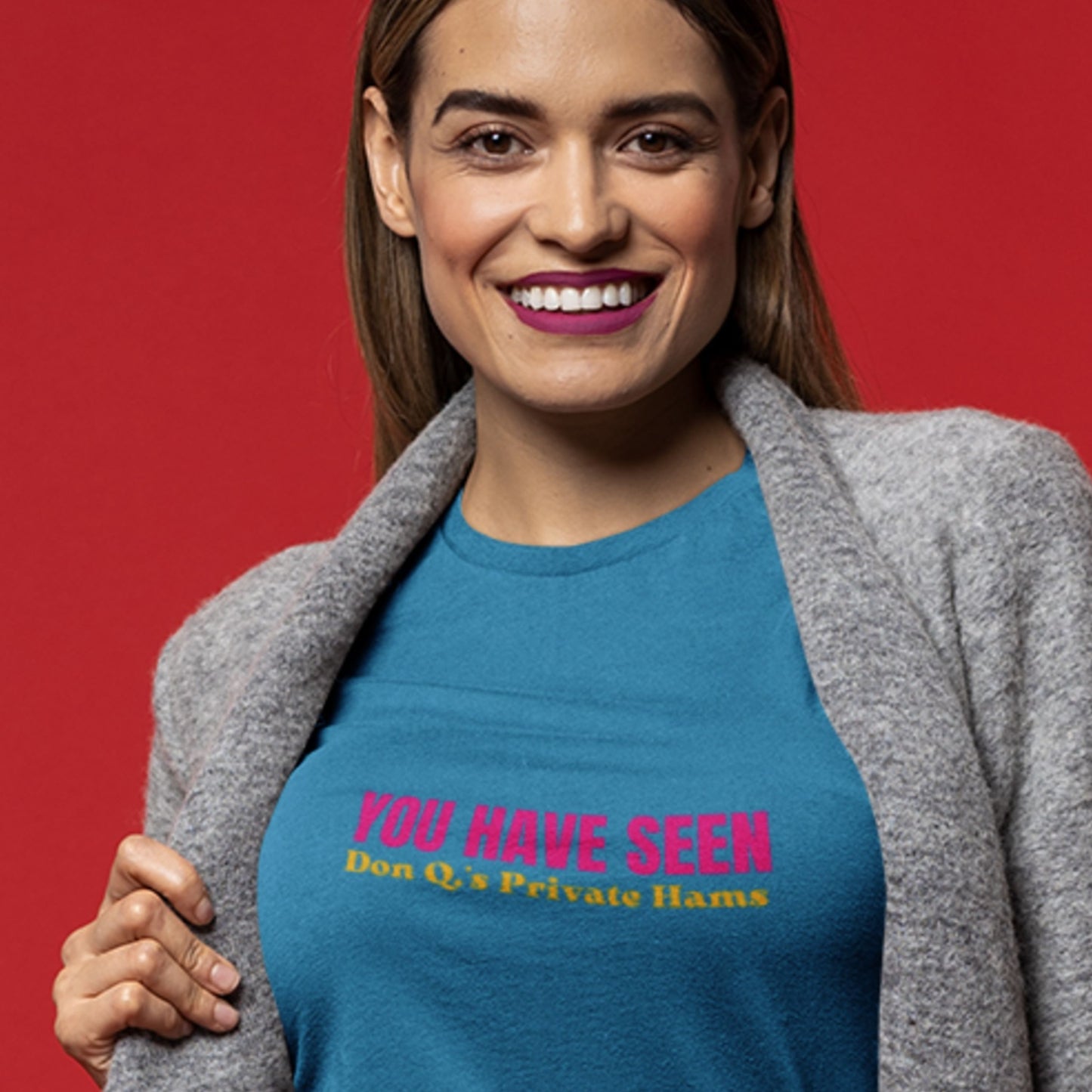 Woman wearing an aqua blue t-shirt with nonsensical multi-colored text on a beige background.