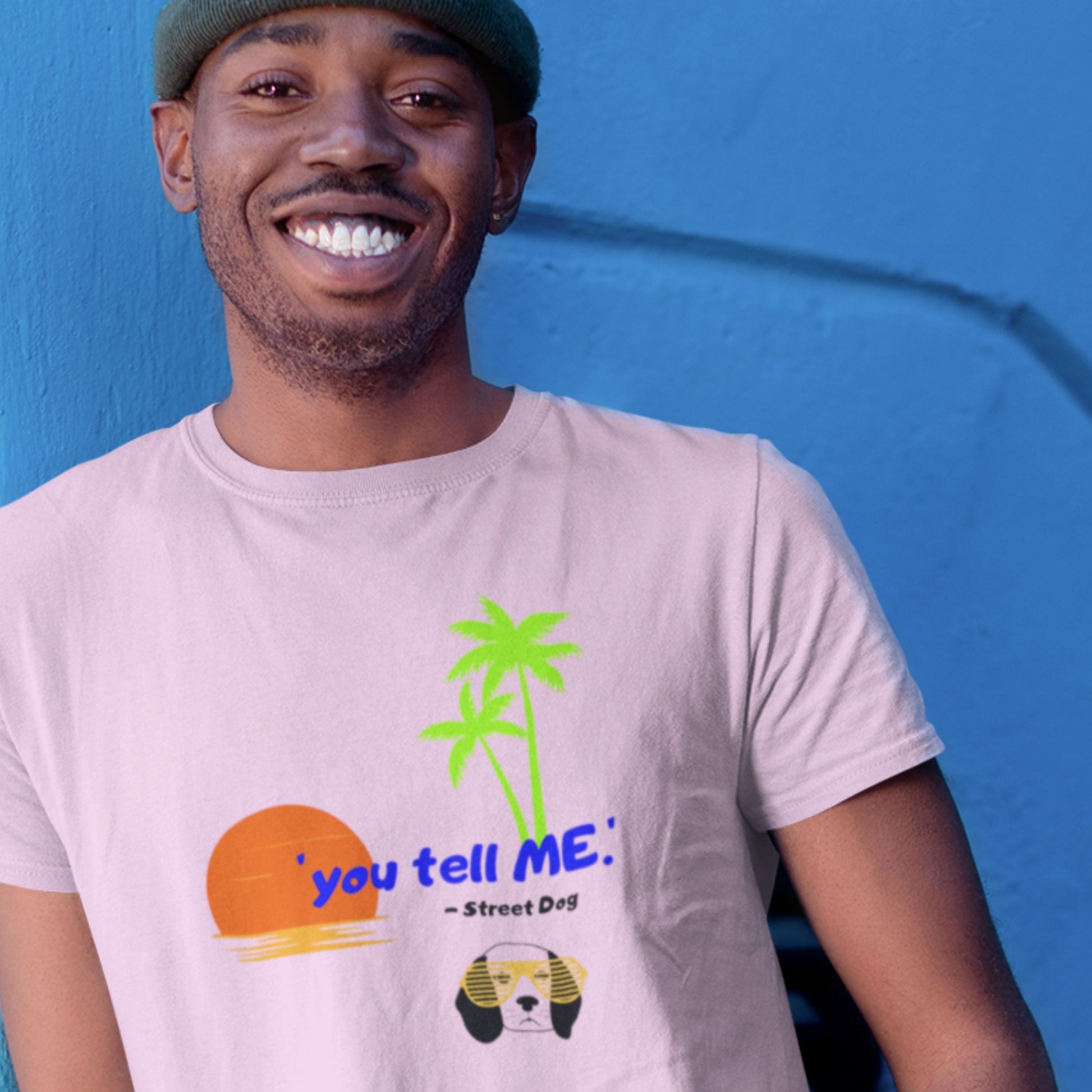 Man wearing a light purple t-shirt with a 90's era graphic design against a blue wall.