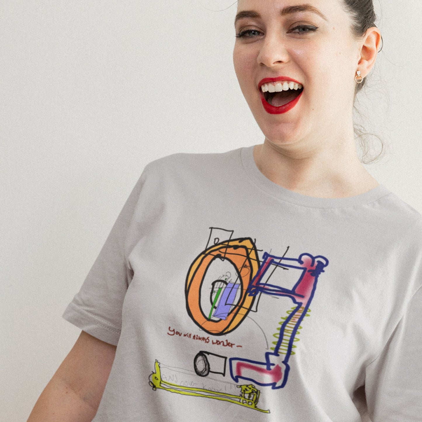 Woman wearing a gray t-shirt with a colorful graphic design on a plain background.